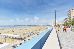 ein Strand mit einem blauen Zaun und Menschen am Strand in der Unterkunft À 150m de la Grande Plage des Sables d'Olonne in Les Sables-dʼOlonne