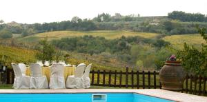 a group of white chairs sitting next to a pool at Agriturismo & Winery Il Bacio in Tavarnelle Val di Pesa