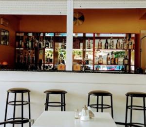 un bar con due tavoli e tre sgabelli da bar di Hotel Orama-Matala a Mátala