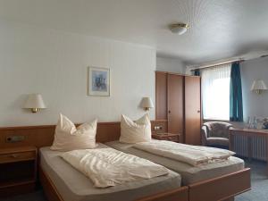 a hotel room with two beds with white pillows at Meyers Gasthof in Bothel