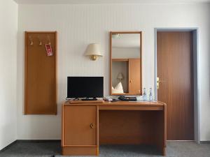 Cette chambre comprend un bureau avec un moniteur et un miroir. dans l'établissement Meyers Gasthof, à Bothel