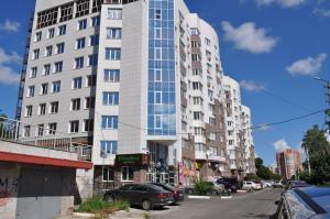 a tall white building on a city street with cars at Студия на Володарского 70/ Studio in the center of Kursk in Kursk