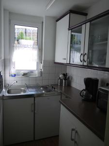 a kitchen with white cabinets and a sink and a window at Schwalbe Hochdorf An der Hohlgasse in Freiburg im Breisgau