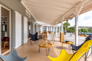 un patio con sillas y mesas en una casa en Villa du Cap 5 étoiles piscine spa et vue mer exceptionnelle, en Sainte-Anne