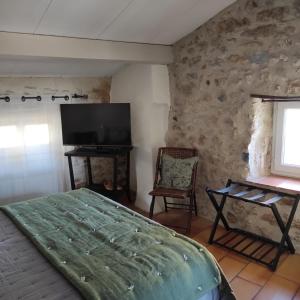 a bedroom with a bed and a flat screen tv at Chambres du clocher in Vallon-Pont-dʼArc