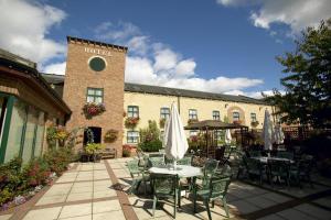 a patio with a table and chairs and a building at Corn Mill Lodge Hotel in Leeds