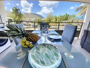 a table with a pineapple and wine glasses on a balcony at From Paris to SXM - luxury next to Anse Marcel Beach in Anse Marcel 