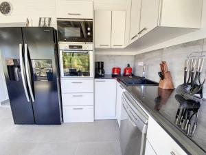 una cucina con armadietti bianchi e frigorifero nero di From Paris to SXM - luxury next to Anse Marcel Beach ad Anse Marcel