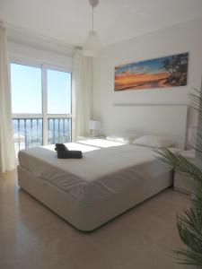 un grande letto bianco in una camera da letto con una grande finestra di Apartamento Sierramar Mijas a Mijas