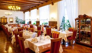 una sala da pranzo con tavoli e sedie bianchi e finestre di Hotel Mondschein a Vipiteno