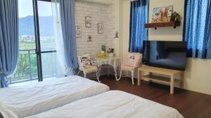 1 dormitorio con 2 camas, mesa y TV en 上雅居, en Sanxing