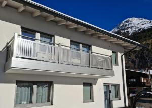 - un bâtiment blanc avec un balcon offrant une vue sur la montagne dans l'établissement Apart Elluto, à Sölden