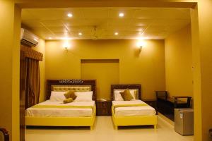 two beds in a room with yellow walls at Hotel Day In Lahore in Lahore