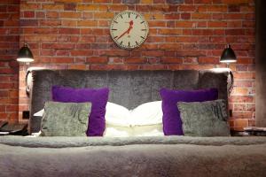 a brick wall with a clock above a bed with pillows at Malmaison London in London