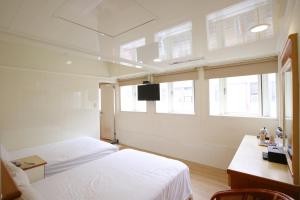 een slaapkamer met 2 bedden, een bureau en ramen bij Lion Hotel in Luodong