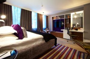 a hotel room with a bed and a desk in a room at Malmaison London in London