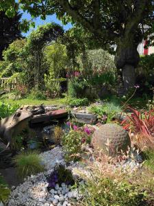 einen Garten mit einem Teich und ein paar Blumen und einem Baum in der Unterkunft Aggarthi Bed and Breakfast in Bayeux