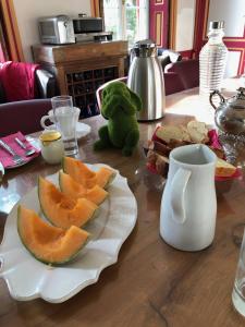 a table with a plate with slices of fruit on it at Aggarthi Bed and Breakfast in Bayeux