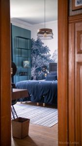 Un dormitorio con una cama azul y una lámpara de araña. en Maison Blanche Chartres - Maison d'hôtes 5 étoiles, en Chartres
