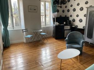 uma sala de estar com um sofá, uma cadeira e uma mesa em Suite privative dans maison de caractère em Le Faou