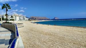 a beach with a blue fence and the ocean at Apartamento Llimera Altea in Altea