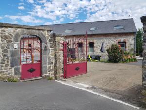 an old stone building with two red doors at Duplex Swimming Cats in Saint-Hilaire-sur-Helpe