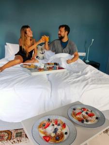 Ein Mann und eine Frau, die auf einem Bett mit Teller Essen sitzen. in der Unterkunft Villa Nestor in Ingenio