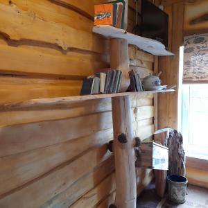 a shelf on the wall of a log cabin at Viesu māja Kaķis krūzē in Folvarcīši +8 photos