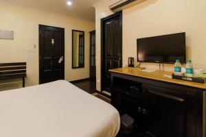 a hotel room with a bed and a flat screen tv at amã Stays & Trails La Maison Fontainhas in Panaji