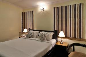 a bedroom with a large bed with two lamps on tables at amã Stays & Trails La Maison Fontainhas in Panaji