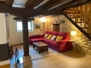 un sofá rojo en una sala de estar con una pared de piedra en Alojamiento Rural El Molino de Butrera, en Butrera