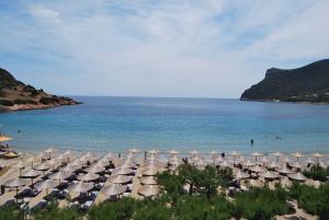 una playa con sombrillas y gente en el agua en Lemon Tree Inn, en Markopoulo