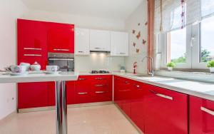 a red kitchen with white appliances and red cabinets at Apartman Lana in Šilo