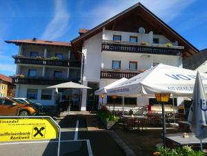 ein Gebäude mit Tischen und Sonnenschirmen davor in der Unterkunft Gasthaus Krone in Übersaxen