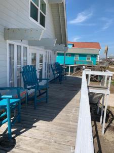 a deck with chairs and tables and a house at Salty Poodle Cottage in Freeport