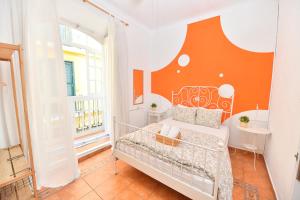 a bedroom with a bed with an orange wall at La Casa Mata Central in Málaga