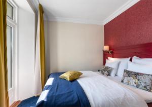 a bedroom with a large bed with a red wall at ProfilHotels Copenhagen Plaza in Copenhagen