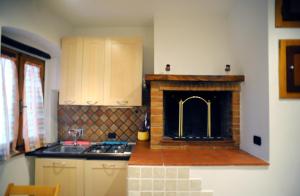 a kitchen with a fireplace with a sink and a stove at Appartamento Tulipano Rosa in Spoleto