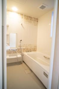 a white bathroom with a tub and a sink at 渡 - Duo Okinawa in Onna