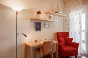 a room with a desk and a red chair and a lamp at Metaxa Seafront Apartment in Perea +26 photos
