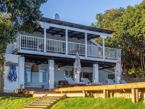 a large white house with a deck and chairs at River House in Plettenberg Bay