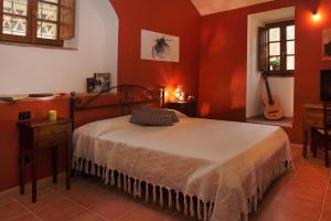 Un dormitorio con una cama con paredes rojas y una guitarra en Antico Borgo De' Frati, en San Gimignano
