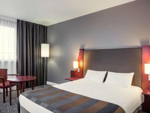 a hotel room with a large bed and a table at Mercure Paris Val de Fontenay in Fontenay-sous-Bois