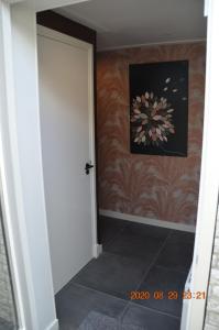 un pasillo con una puerta y una pintura en la pared en B&B De Kamer, en Wervershoof