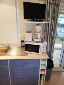 cocina con microondas y cafetera en una encimera en Mobil home climatisé ETANG DE BESSE, en La Parée Preneau