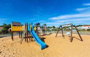 un parque infantil con un tobogán azul en la arena en Mobil home climatisé ETANG DE BESSE, en La Parée Preneau