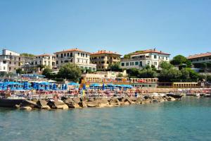a beach with umbrellas and people on the water at Appartamenti fronte mare in Castiglioncello