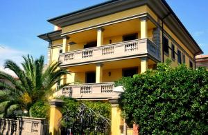 a yellow building with white balconies and a palm tree at Appartamenti fronte mare in Castiglioncello