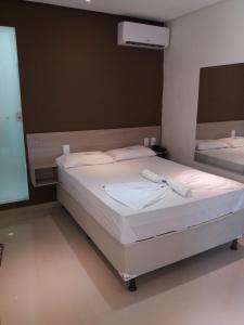 um quarto com uma cama grande e lençóis brancos em Boca do Rio Hotel em Salvador