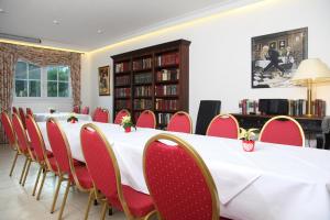 una sala de conferencias con una mesa larga y sillas rojas en Hotel Fürstenberg, en Essen